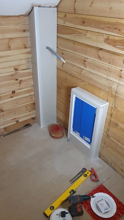 Renoveringsprojekt med delvis installerat eluttag, verktyg och material på ett trägolv.