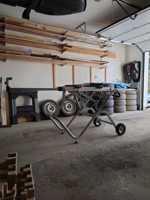 Ett nytt sågbord fullt utdraget i ett garage, med hjul och skruvar ordentligt monterade.