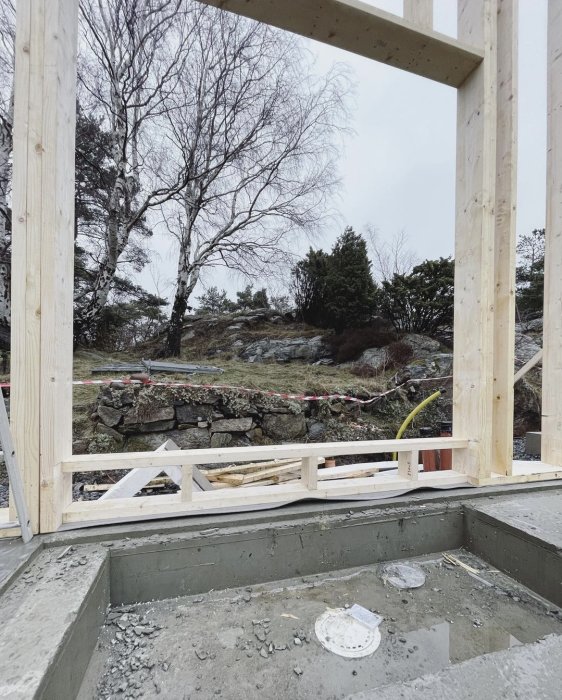 Nybyggt badkar i betong med utsikt genom en stor öppning i en byggarbetsplats.