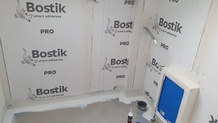 Renovering av ett badrum med väggar täckta av Bostik-vattentätningsskivor, murbruk och installationsrör.