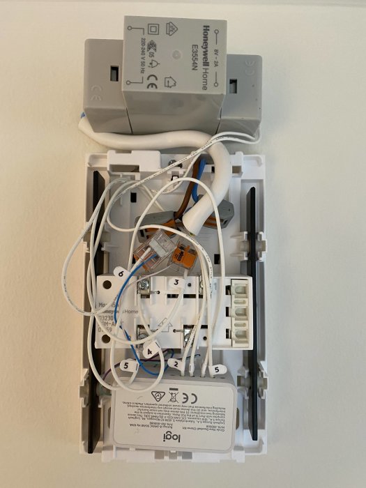 Öppen eluttag där en termostat är delvis installerad med synliga ledningar och installationsanvisningar.