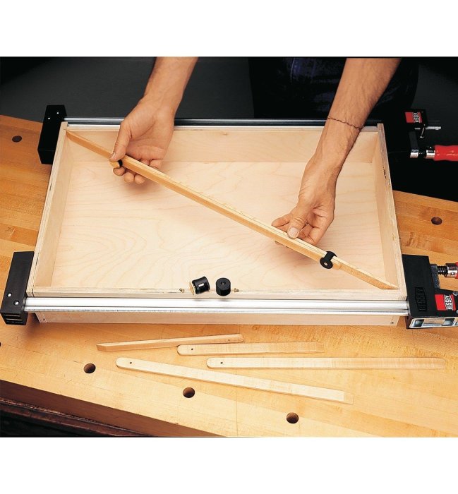 En person mäter diagonalen i en låda med en justerbar trämätsticka för att säkerställa vinkelrätthet.