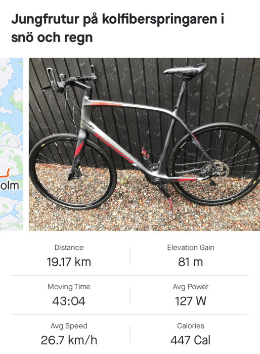 Svart kolfibercykel lutad mot trävägg med statistik från cykeltur: 19.17 km avstånd, 81 m höjdökning.