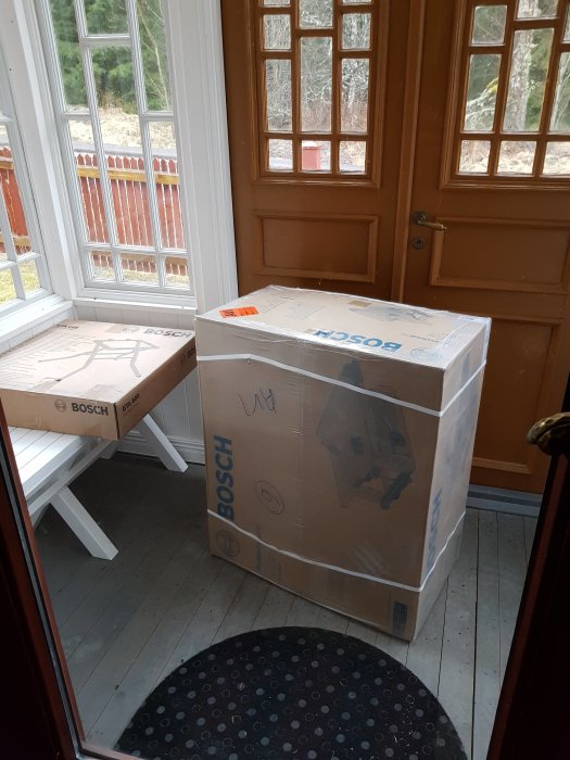 Opackade lådor med Bosch klyvsågar som står i en hall vid en öppen ytterdörr.