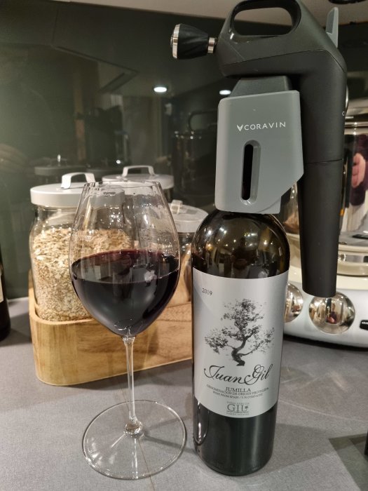 Vinflaska med etiketten "Juan Gil" och ett glas rödvin, Coravin vinsystem på flaskan.