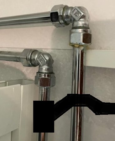 VVS-installation med T-koppling och rör som går i 90-graders vinkel ovanför en svart redigerad del.
