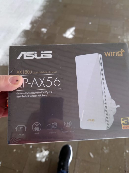 En hand håller en ASUS WiFi 6 repeater låda utomhus, återspeglar förbättring av WiFi-täckning hemma.