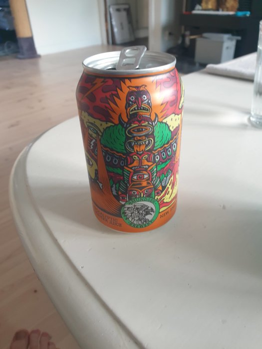 En färgglad burk barly wine med konstnärlig design står på ett vitt bord.