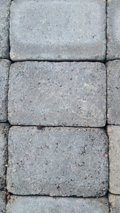 Närbild av markstenar med varierande textur och kvalitet ligger bredvid varandra på marken.