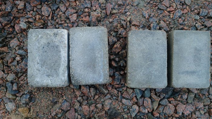 Fyra markstenar jämförs på grusunderlag, de två till höger har ojämn baksida.