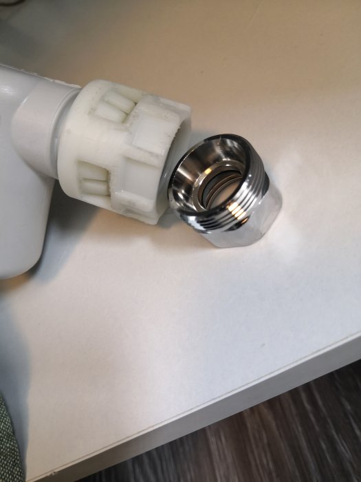 Vattenläckage vid gängad koppling mellan vit PVC-komponent och metallnippel.