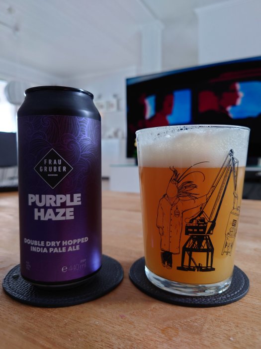 En burk Frau Gruber Purple Haze öl och ett glas med ölen framför en TV.