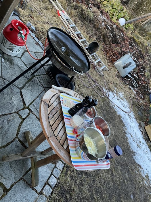 Förberedelse för matlagning av paella utomhus med ingredienser och stekpanna på gasolbrännare.