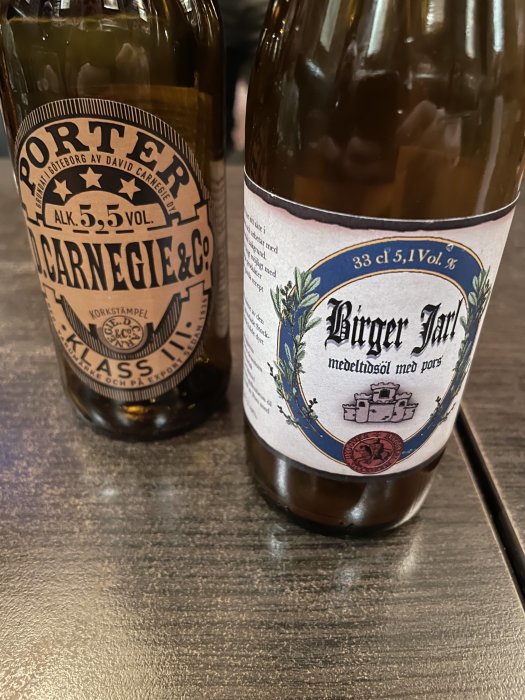 Två svenska ölflaskor, Carnegie Porter och Birger Jarl, på ett bord.