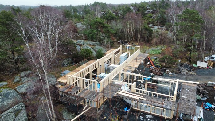 Byggarbetsplats med stomresning av träramar för ett hus på bergig terräng.