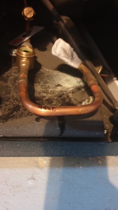 En ihopfrysen expansionsventil med synliga isbildningar och anslutna kopparrör på en värmepumpsinstallation.