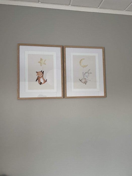 Två tavlor på en vägg med barnvänliga illustrationer av en björn med stjärna och en kanin med måne.