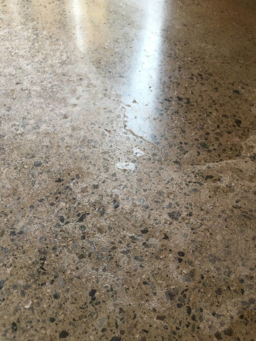 Slipat betonggolv med synliga fläckar och ojämn yta som indikerar möjliga kalkutskjutningar eller skador.