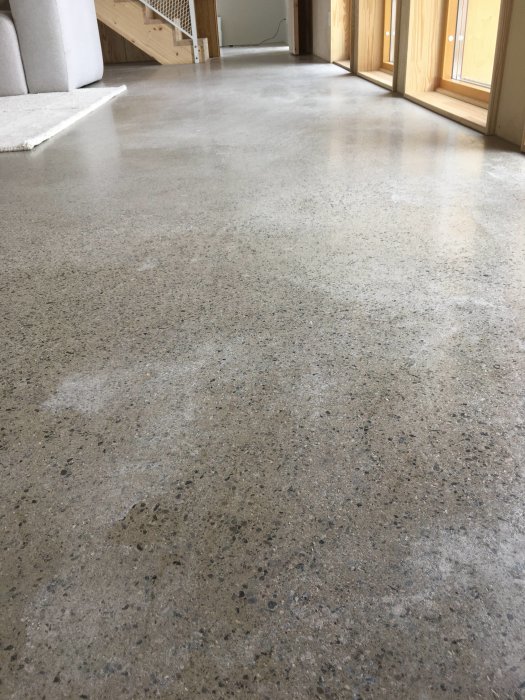 Slipat betonggolv med ojämn yta, märken och potentiella kalkutskjutningar i ett modernt hus.