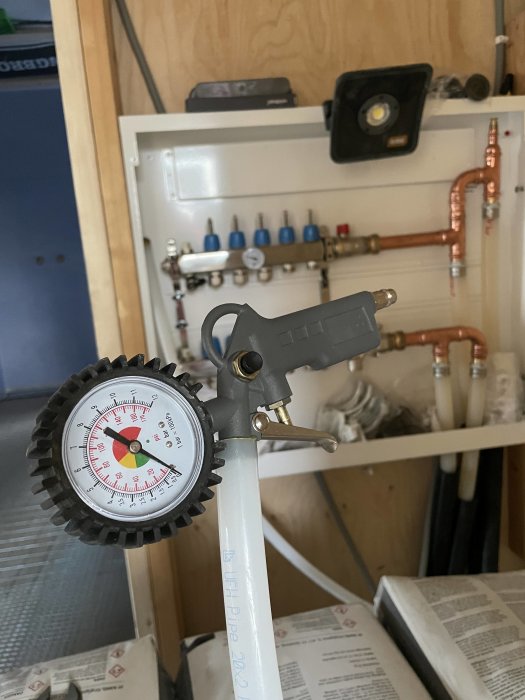 Provtryckning av golvvärme med hjälp av manometer och hemmagjord anordning i en pågående badrumsrenovering.