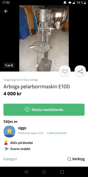 Arboga pelarborrmaskin E100 står i ett verkstadsutrymme med diverse verktyg och material i bakgrunden.