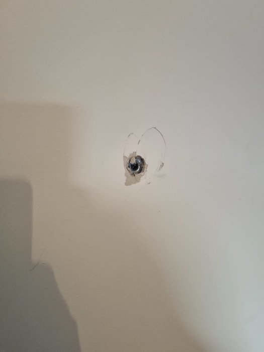 Hål och insjunken Mollyplugg i en vit gipsvägg, behov av lagning inför försäljning.