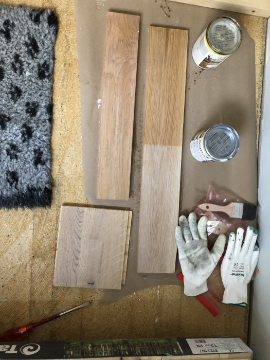 Trösklar i olika behandlingar med Osmo vax, verktyg och arbetsmaterial på ett arbetsbord.