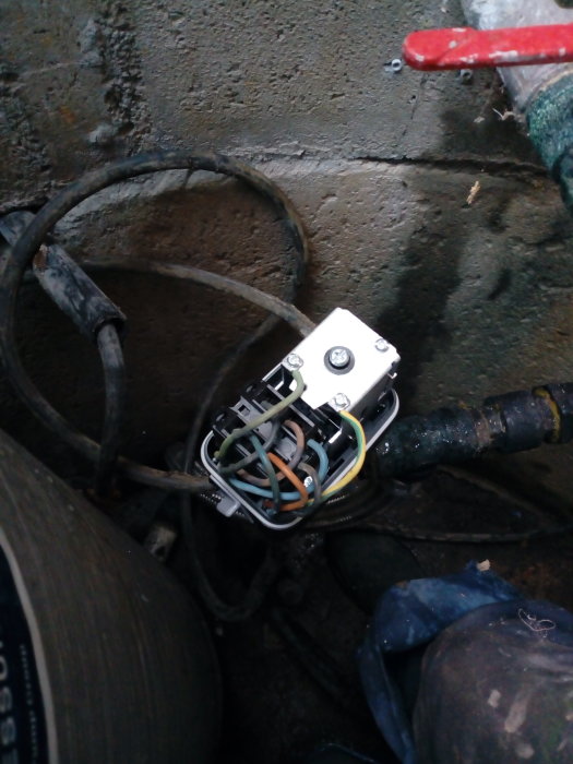 En nyinstallerad elanslutningsdosa med ordnade kablar på en grov betongvägg.