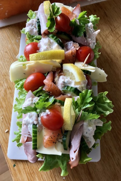 Glutenfri smörgåstårta med räkor, citron, ost, skinka och tomater på salladsbädd.