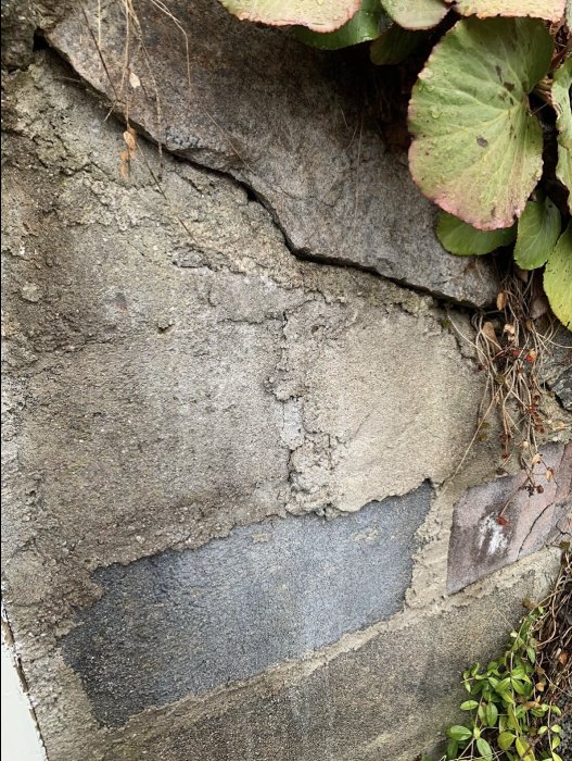 Närbild av en gammal jordkällarvägg av blandade material som natursten och betongblock.