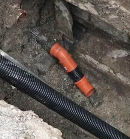 Dräneringsrör med 110mm muffar i en öppen grävd schakt.