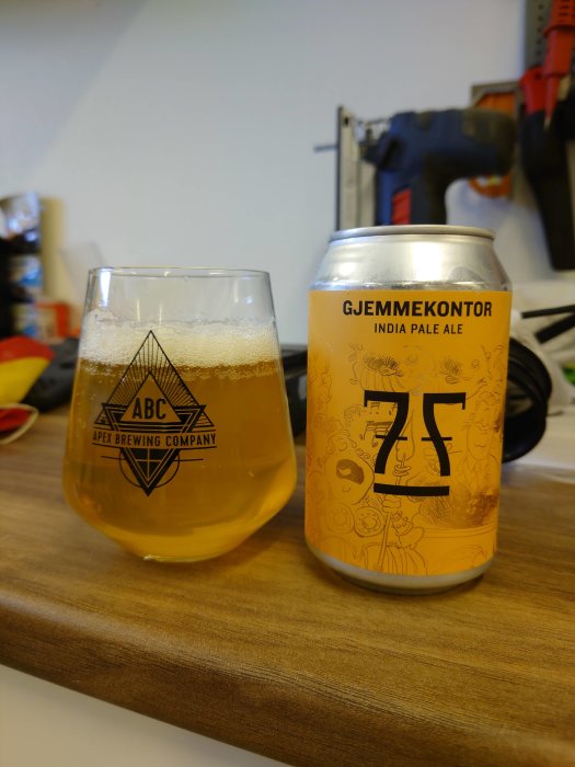 En ölglas med IPA bredvid en burk från 7Fjell, på en träyta med verktyg i bakgrunden.