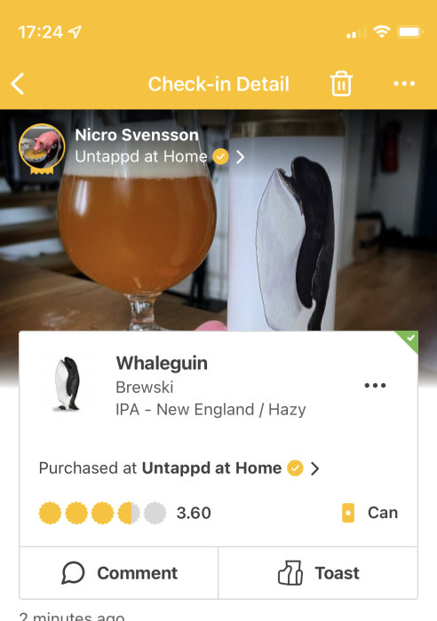 En ölglas fylld med hazy IPA bredvid en burk med valpingvin illustration, betygsatt 3.60 på app.