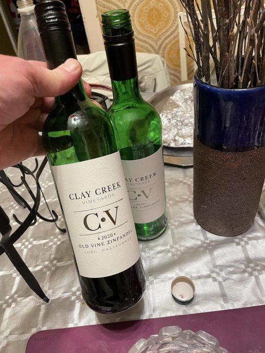 Två flaskor Clay Creek Vineyards Zinfandel vin på ett bord, en öppnad och en stängd, rekommenderas för grillat kött.