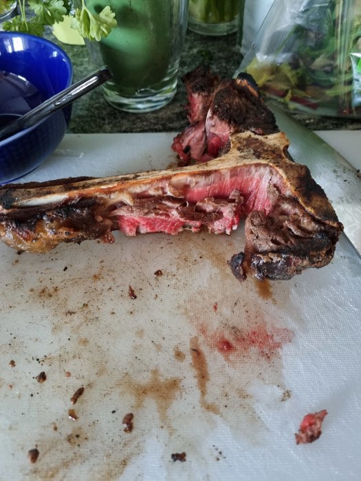 En halvt uppäten hängmörad T-bone steak på en skärbräda med tydliga steksaftspår.