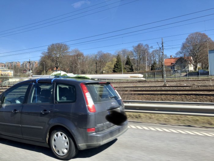 Bil kör på motorväg med löst liggande föremål på taket.