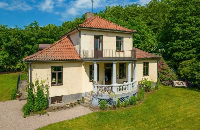 Hus från 1923 med balkong på pelare över en balustrad, spricka inte synlig i bilden.