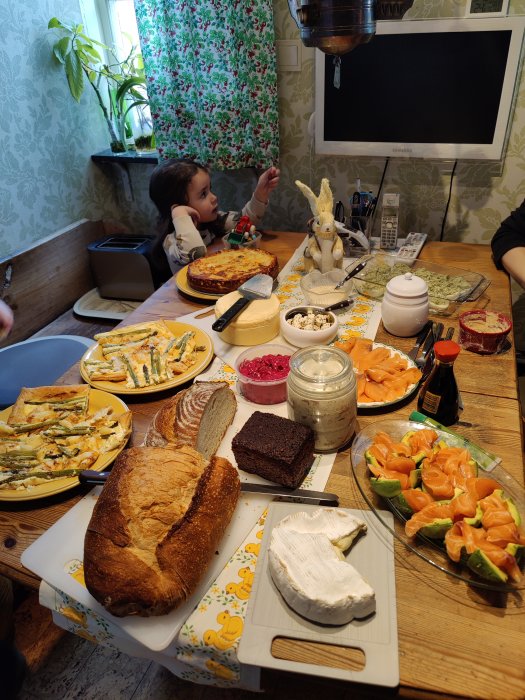Påskbord med olika maträtter och ett barn vid bordet i ett hemmakök.