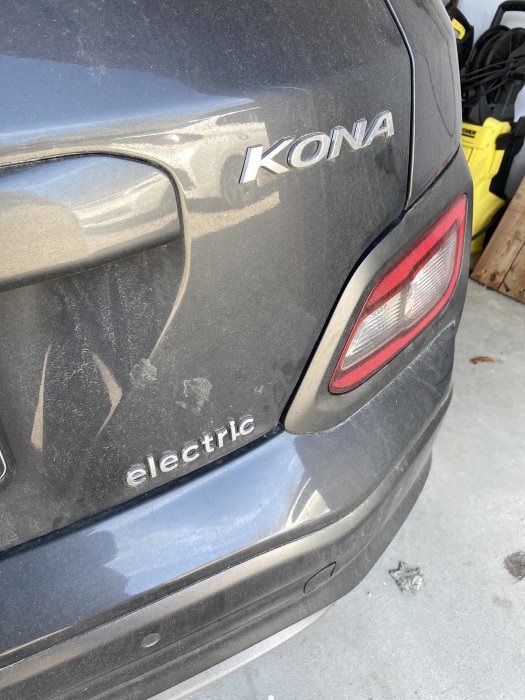 Bakdelen av en smutsig elbil märkt "KONA electric" som avser laddning med solenergi.