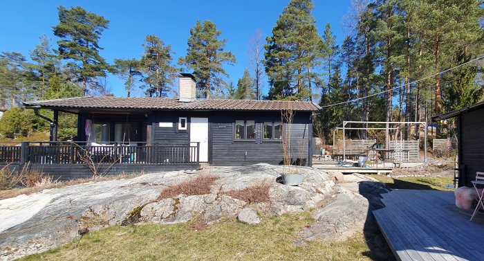 Västkuststuga från 1973 på berg med betongplattor på taket och trädäck, avsedd för tillbyggnad.