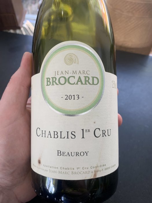 Flaska med vinet Jean-Marc Brocard Chablis 1er Cru från 2013 hållen av en hand.
