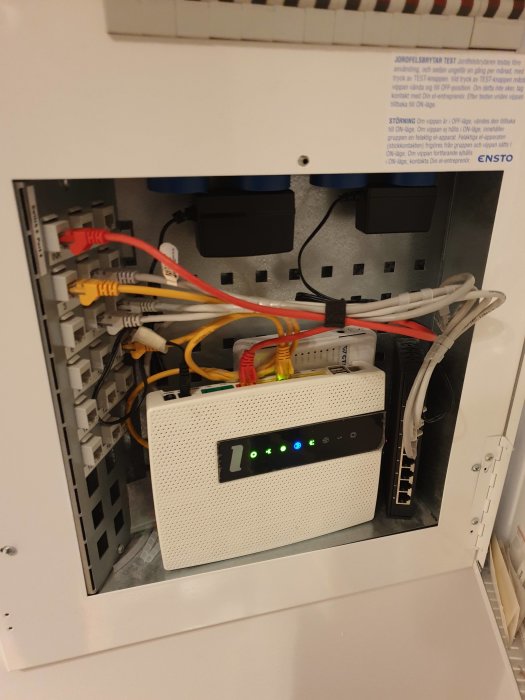 Eluttag och nätverksswitch i en elcentral med anslutna kablar och blocknivåadaptrar.