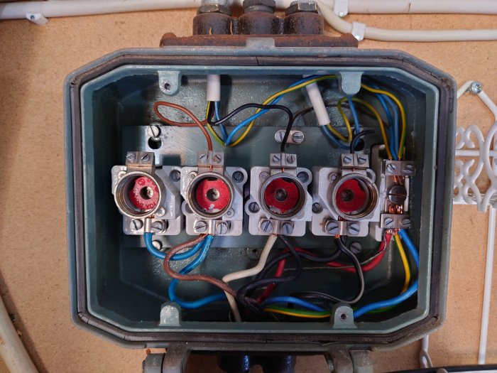 Öppen elektrisk kopplingslåda med flera anslutna kablar och terminaler, fråga om korrekt anslutning.