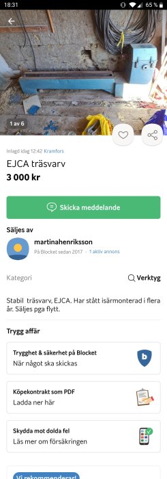 En blå trävarv placerad på ett stenigt och ojämt underlag i en verkstadsliknande miljö med kabelbuntar hängande i bakgrunden.