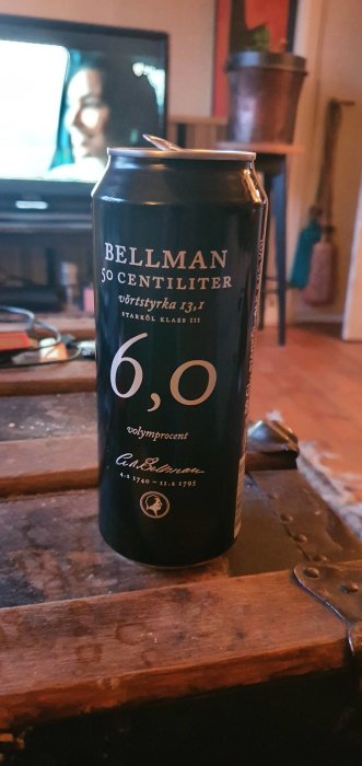Ölburk på bord framför suddig TV, Bellman 50 cl med 6,0% alkoholhalt.