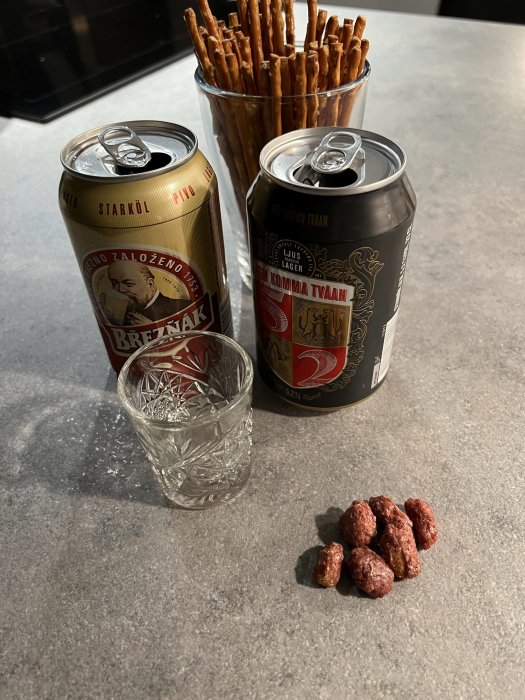 Ölburkar, ett glas och salta pinnar på köksbänk med några jordnötter.