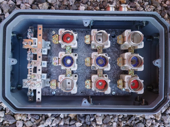 Öppen eldosa med flera kabelanslutningar och säkringselement, redo för elektriska installationer.