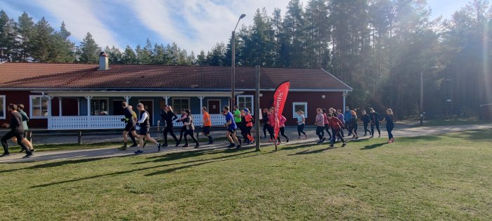 Löpare i en Backyard Ultra, startar tävlingen vid röd byggnad med skogsbakgrund.