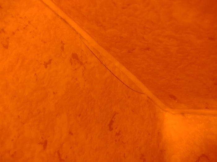 Spricka längs kanten där våtrumsmattans golv möter vägg.