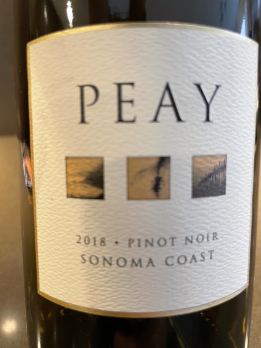 Flaska vin med etiketten "PEAY 2018 Pinot Noir Sonoma Coast" och stiliserade bilder på etiketten.